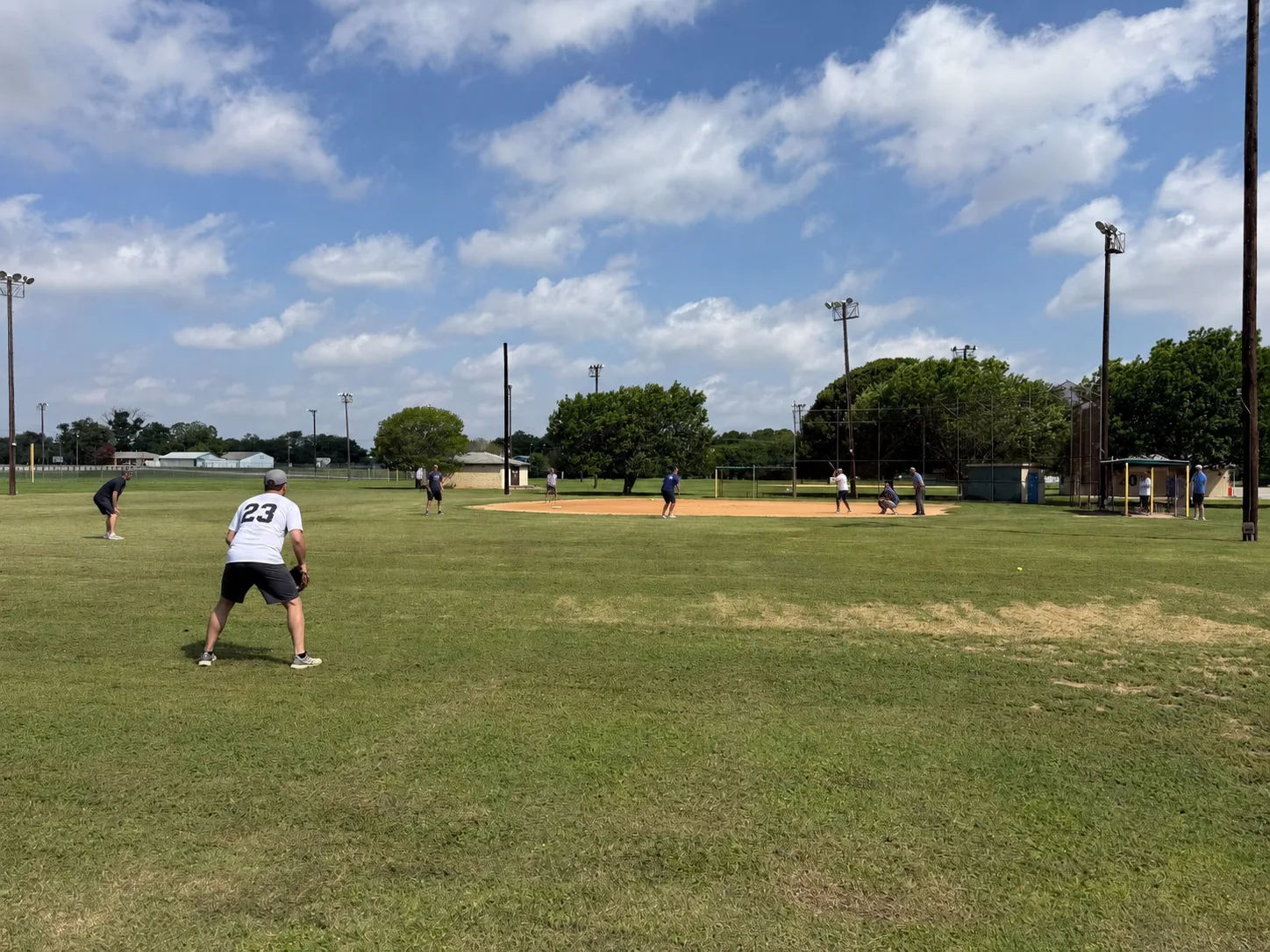 Adults playing a co-ed softball game on a sunny day at Thulemeyer Park in Schertz